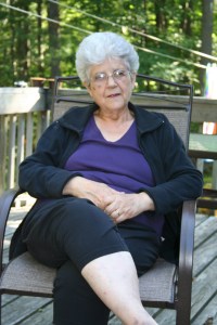 An older woman sits on a deck