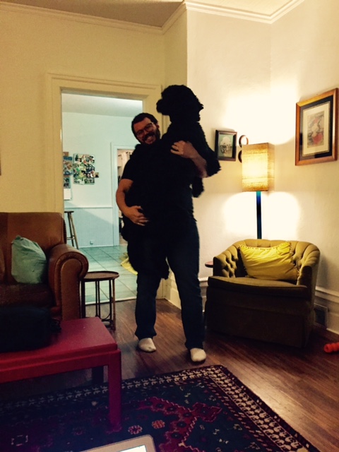 A man holding a giant black dog