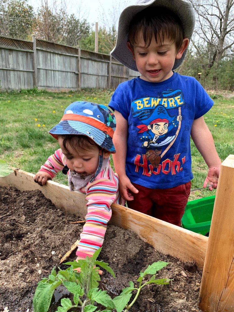 Both kids playing in the veggie box.